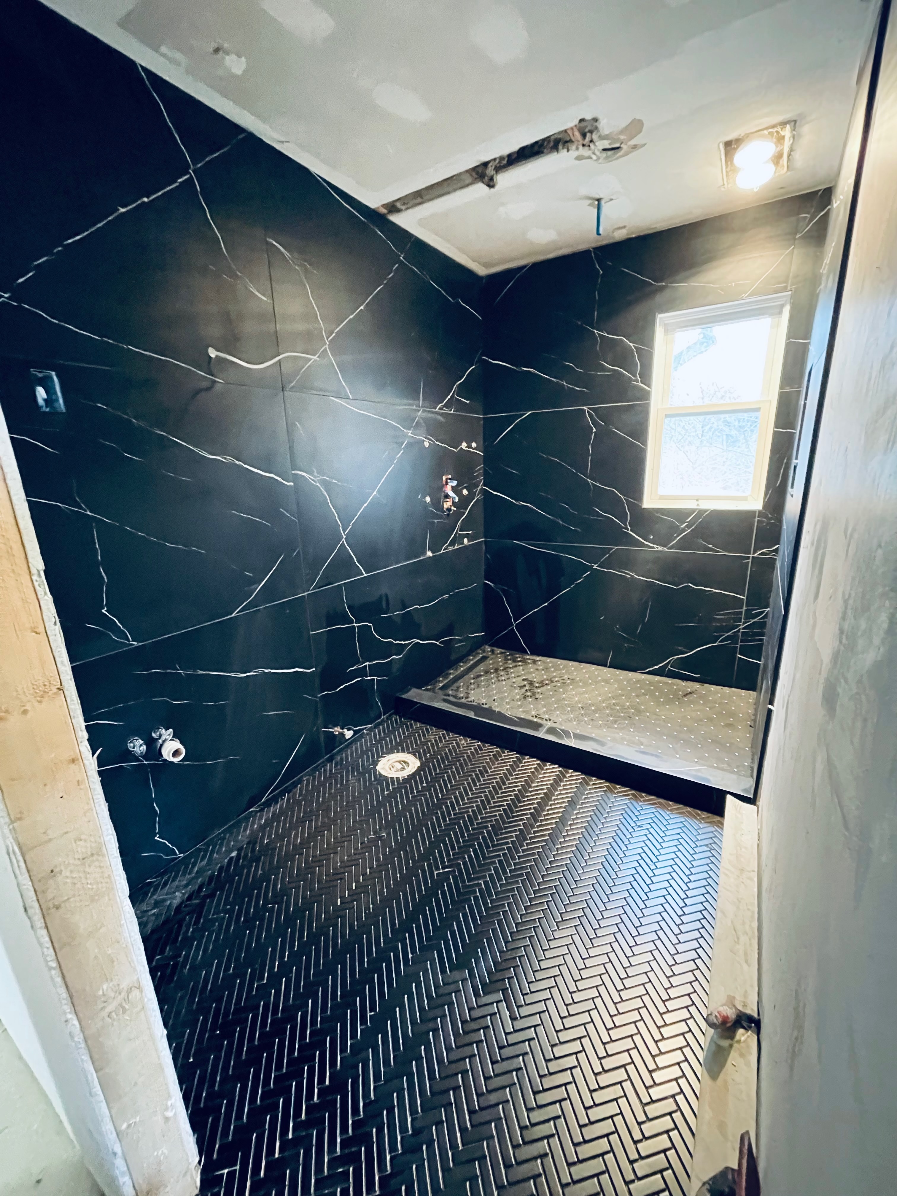 Black marble bathroom with frameless glass shower at 880 Blue Star