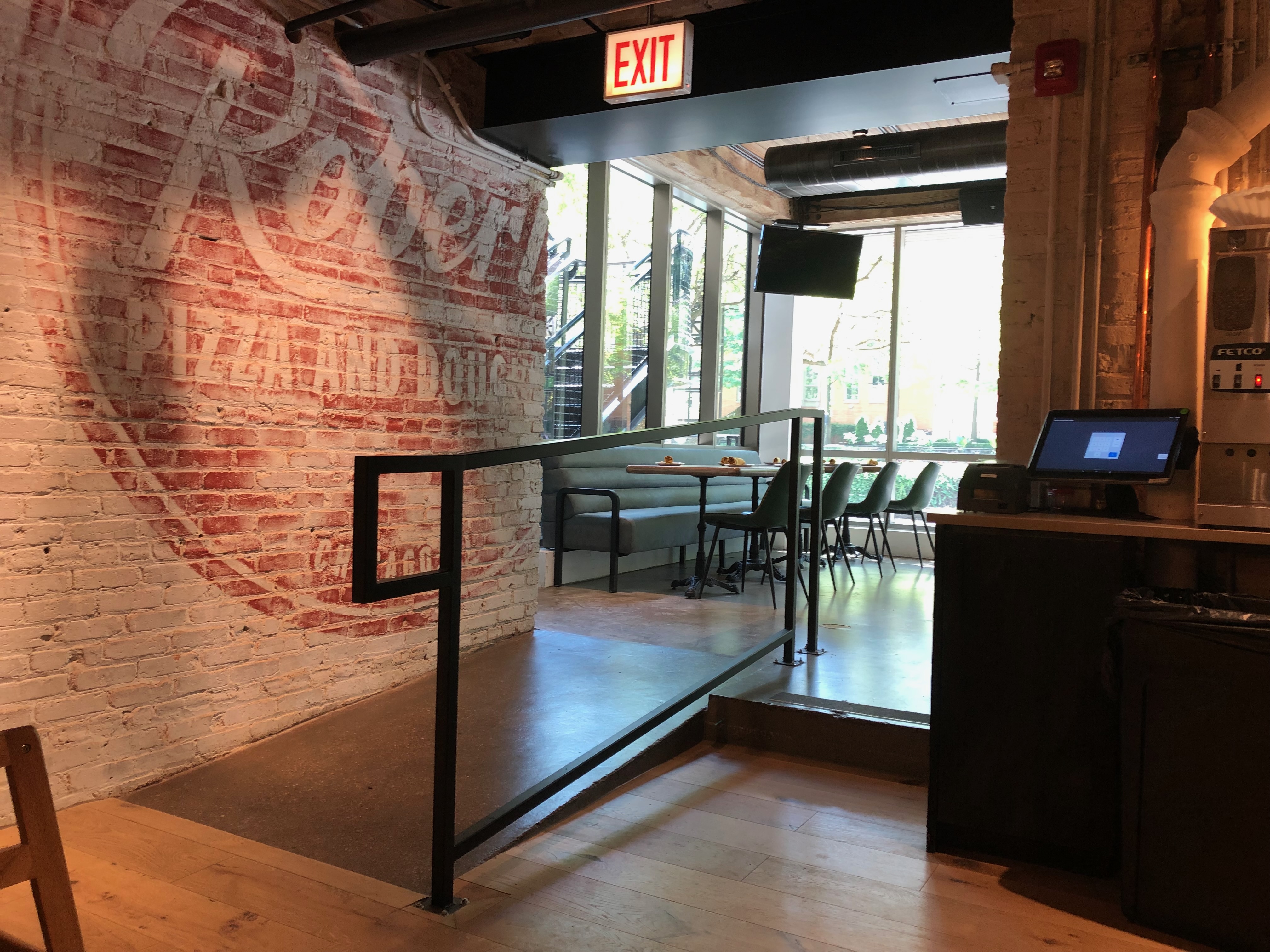 Entry wall with exposed brick and a seated lounge area at Blue Bar