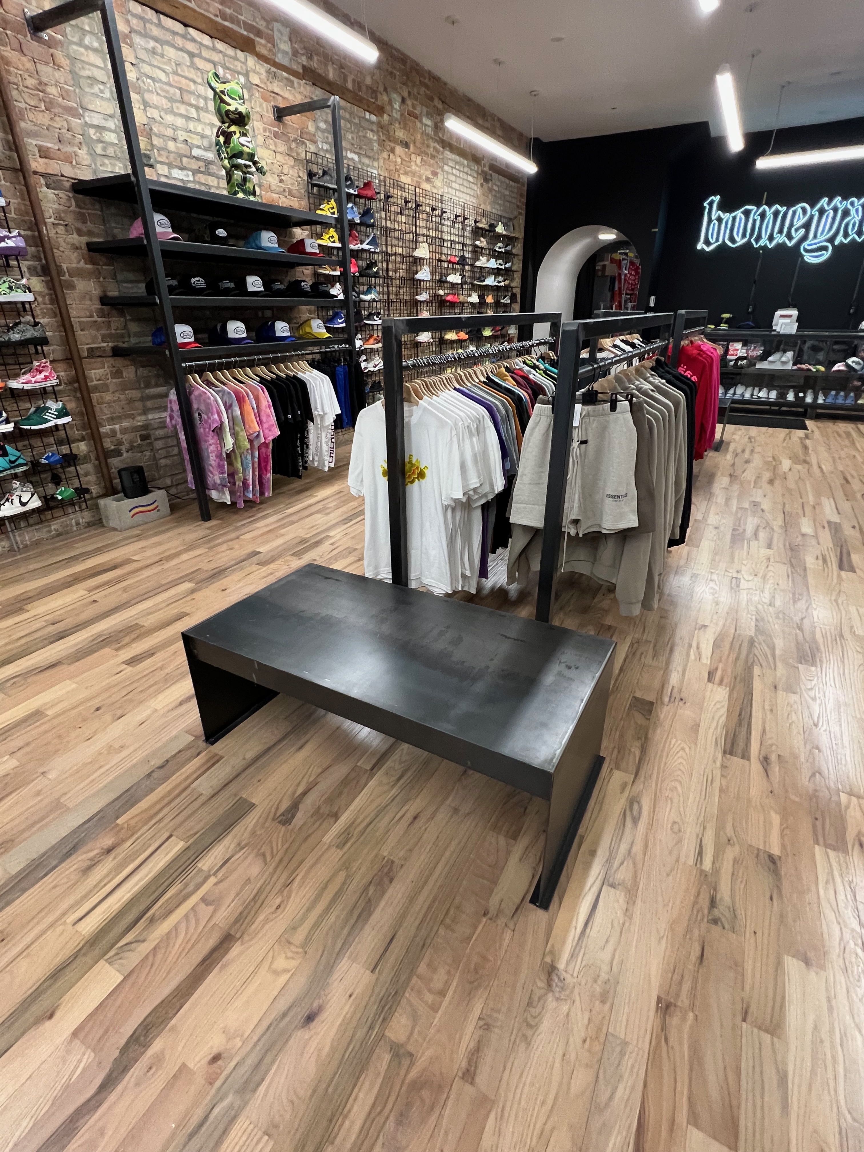 Custom black steel apparel fixtures along the dark side wall inside Boneyard