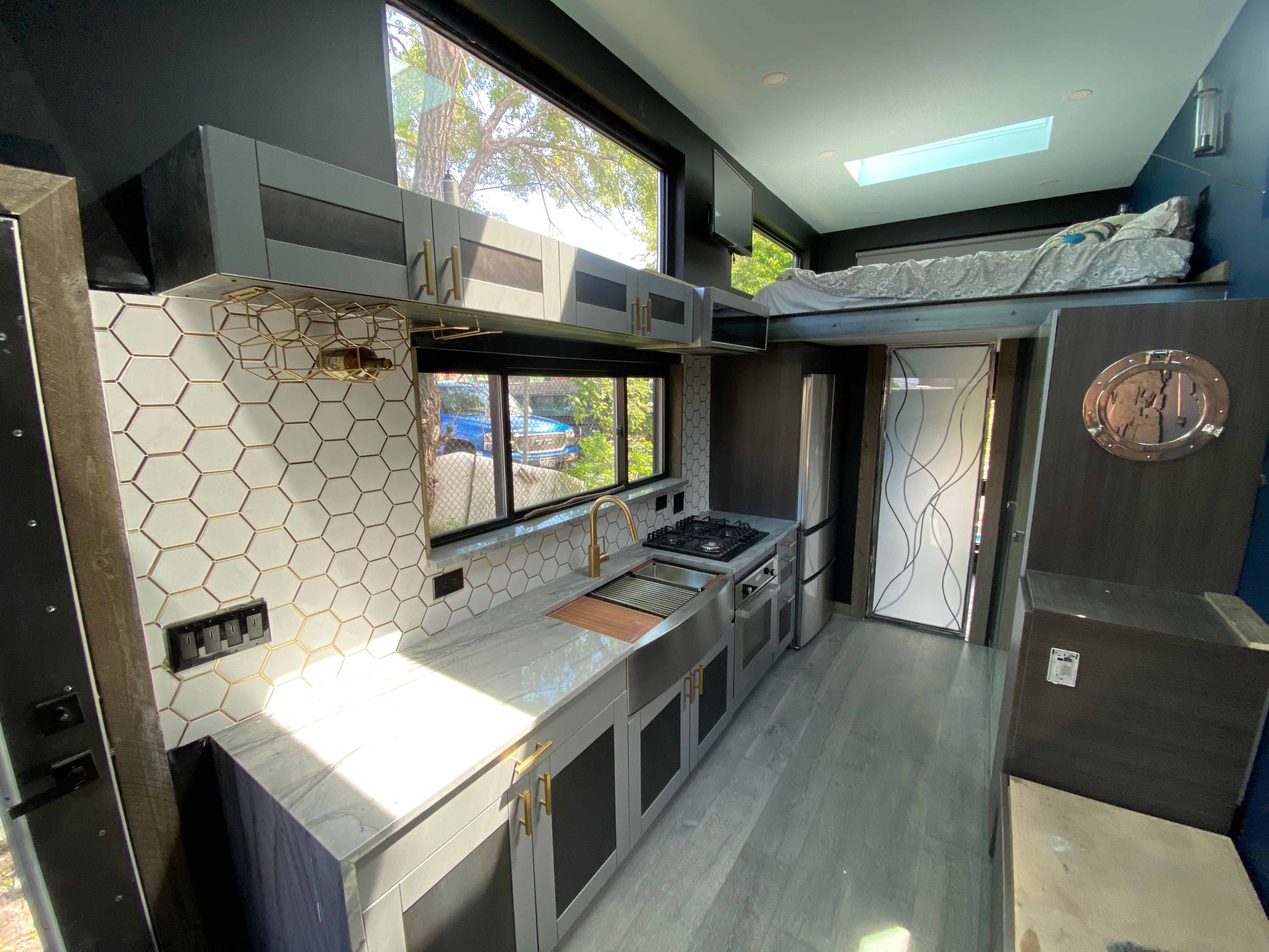 Finished interior view with the kitchenette, loft sleeping zone, and long daylight-filled layout