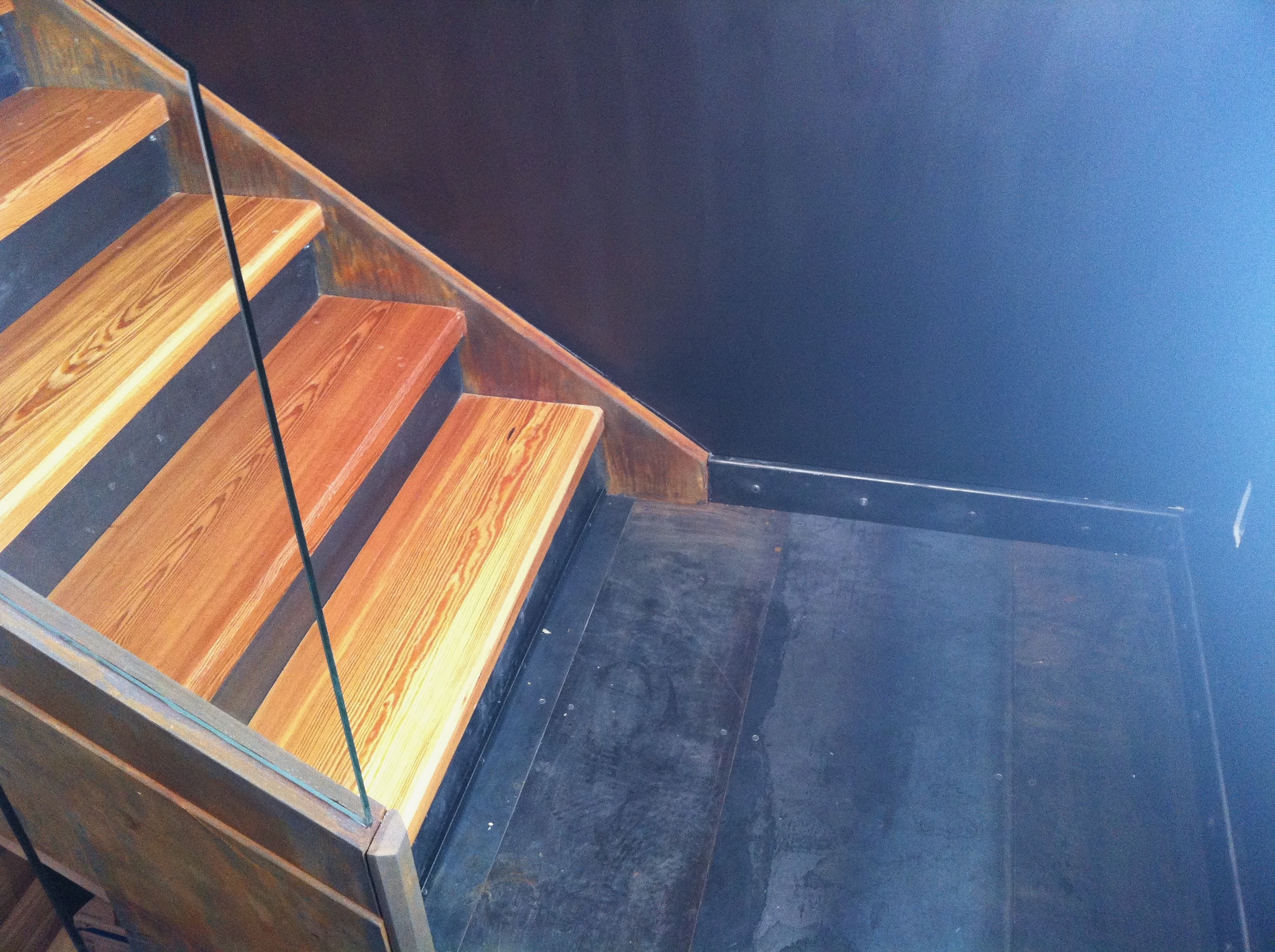 Landing detail of the steel stringer staircase with wood treads and glass guard